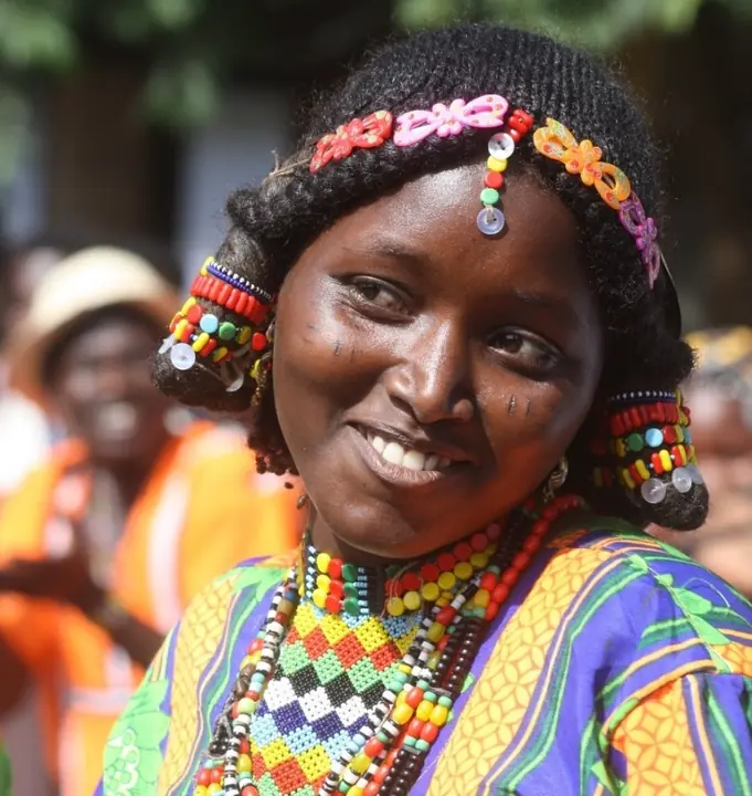 A woman in a beaded headdress, smiling