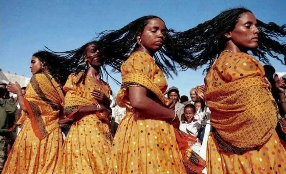 Women dancing in yellow dresses, hair in motion