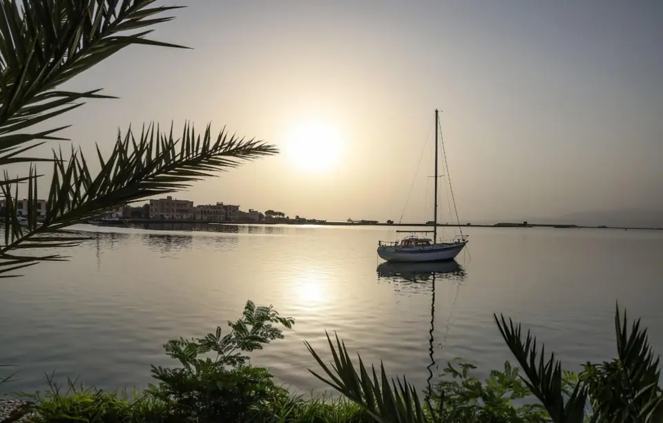 A sailboat in the harbor at sunrise