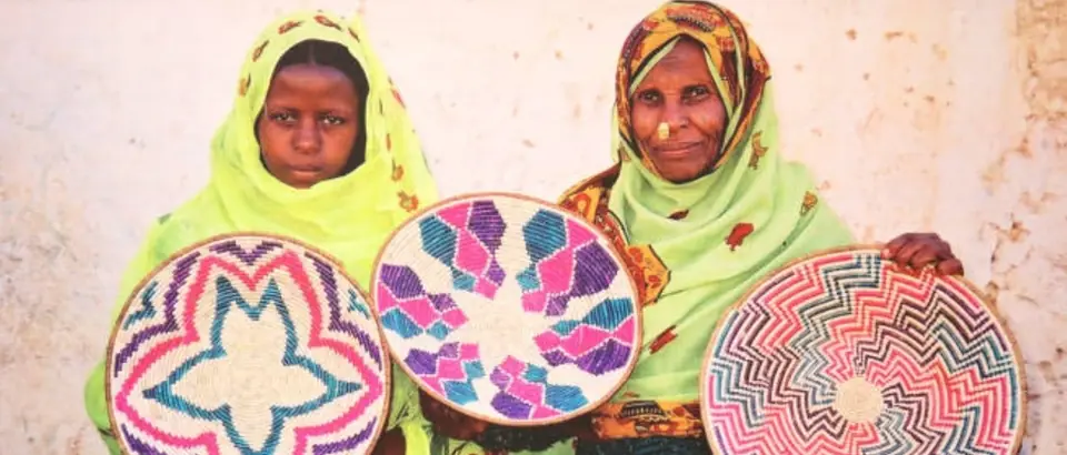 Two women holding hand-woven baskets