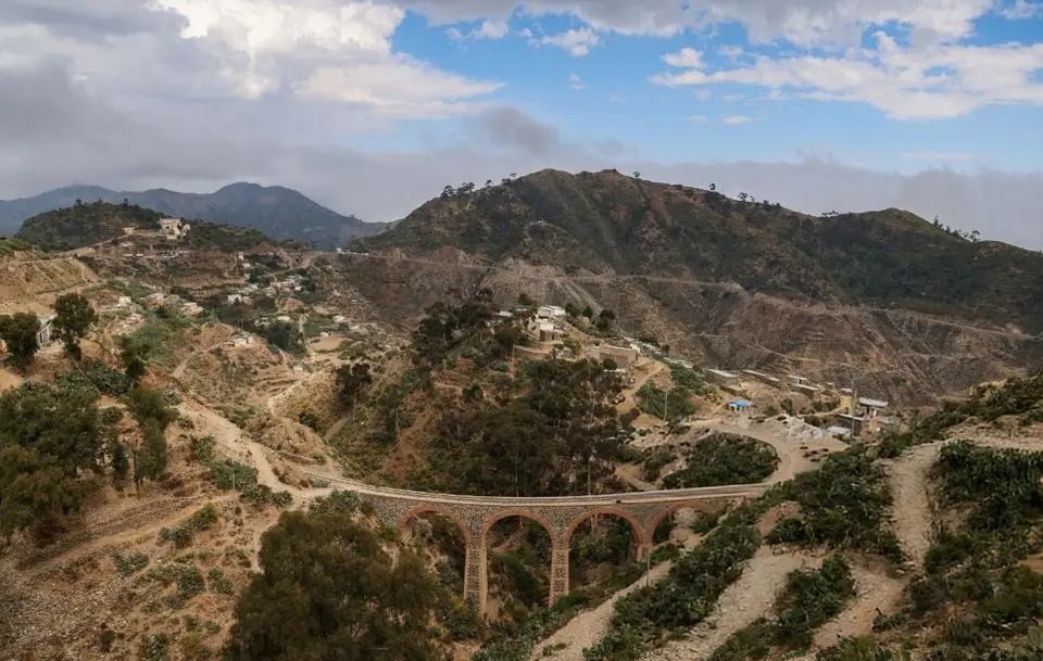 A stone railway bridge across green hills