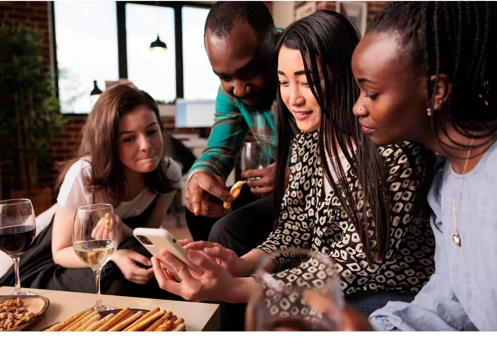 Friends gathered around a phone at a dinner table